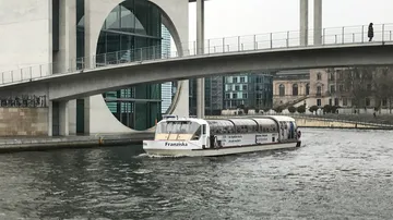 Boat named Franziska under urban bridge.