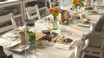 Tisch für Mahlzeit mit Blumen und Geschirr gedeckt.