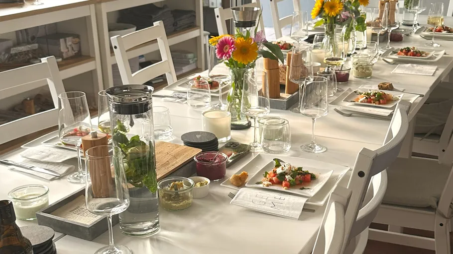 Tisch für Mahlzeit mit Blumen und Geschirr gedeckt.