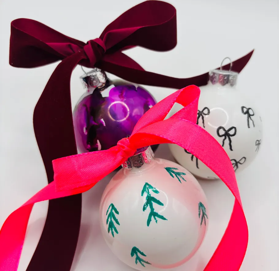 Three decorated Christmas ornaments with bows.