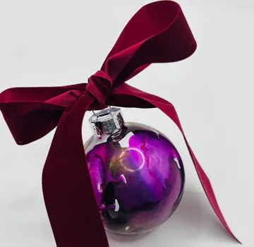 Purple ornament with burgundy ribbon, white background.