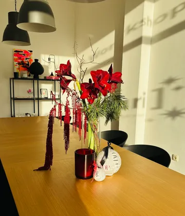 Rote Blumen in Vase auf Holztisch.
