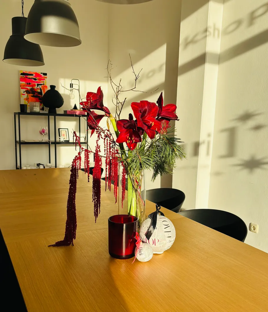 Red flowers in vase on wooden table.