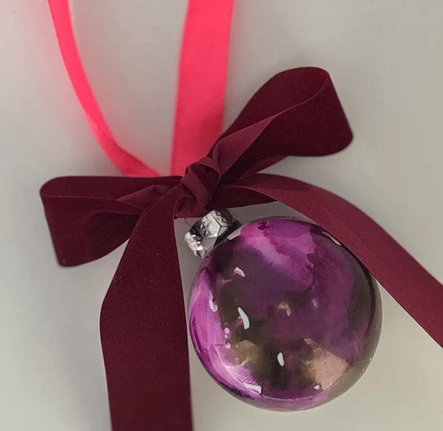 Purple ornament with burgundy bow on wall.