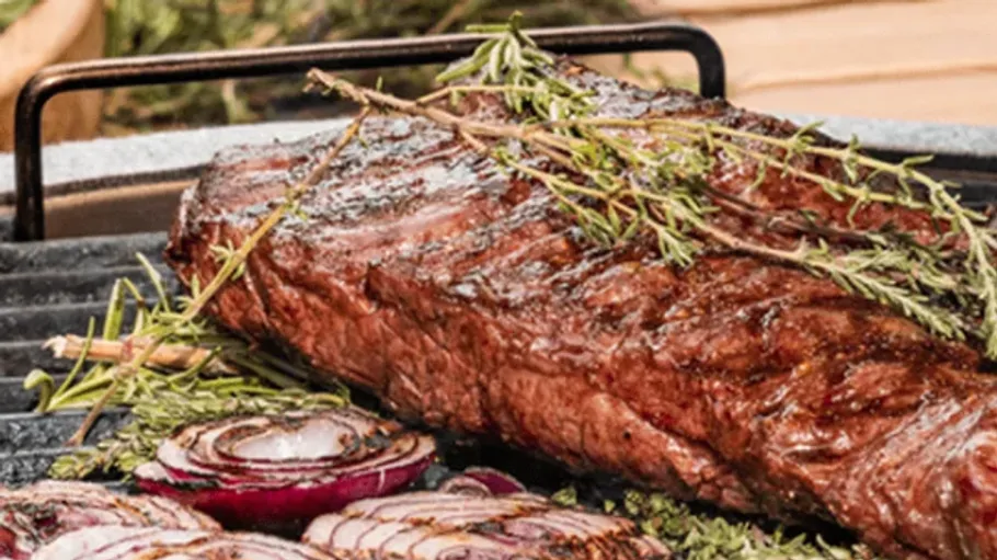 Grilled steak with rosemary on barbecue grill.