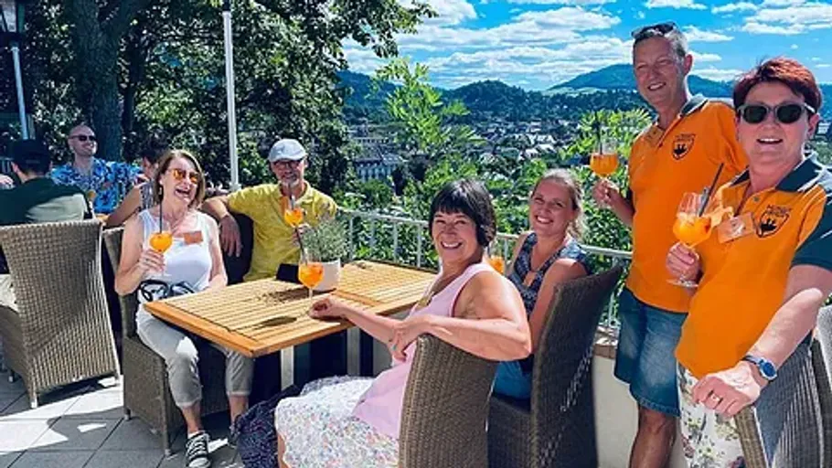 Group enjoying drinks on a sunny balcony.