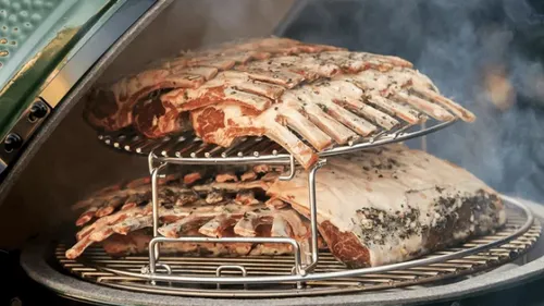 Ribs smoking inside a green ceramic grill.