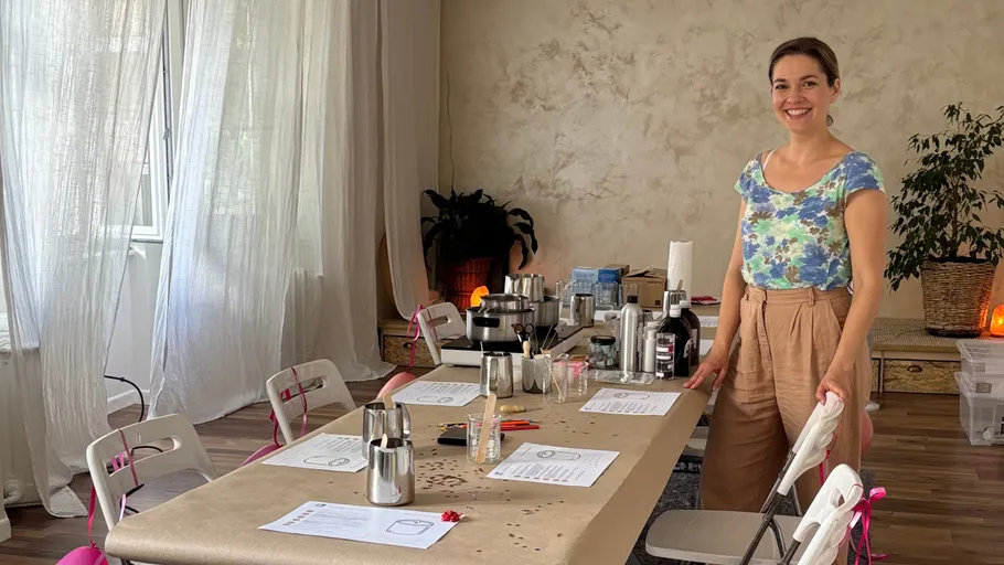 Frau steht an Tisch für Kerzenherstellung.