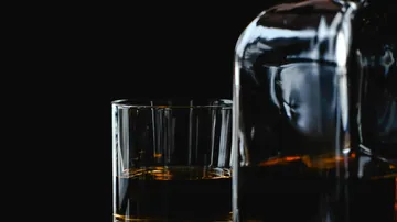 Whiskeyglas neben einer Flasche.