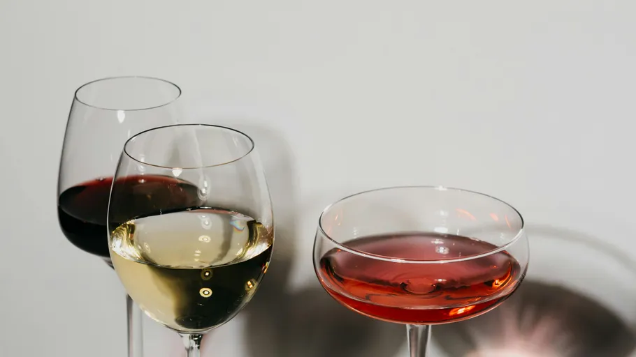 Three glasses of wine against plain background.