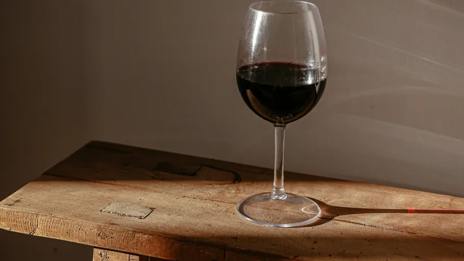 Wine glass with red wine on wooden table.
