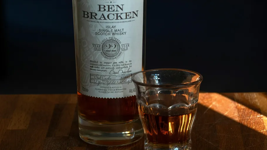 Whisky bottle and glass on wooden table.