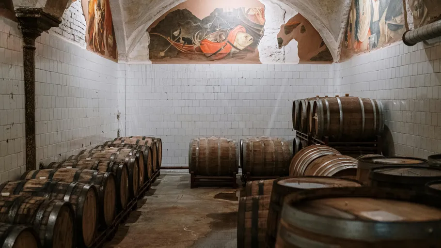 Wooden barrels stored in a tiled cellar.