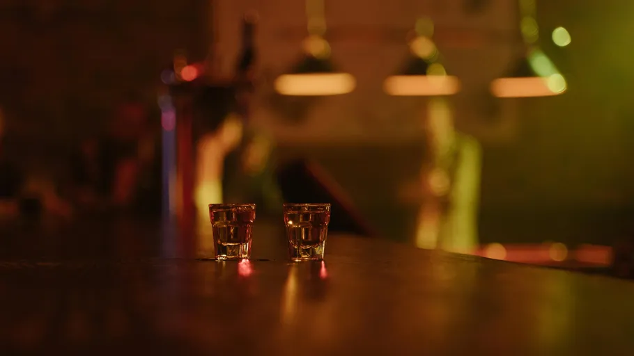 Two shot glasses on dimly lit bar counter.