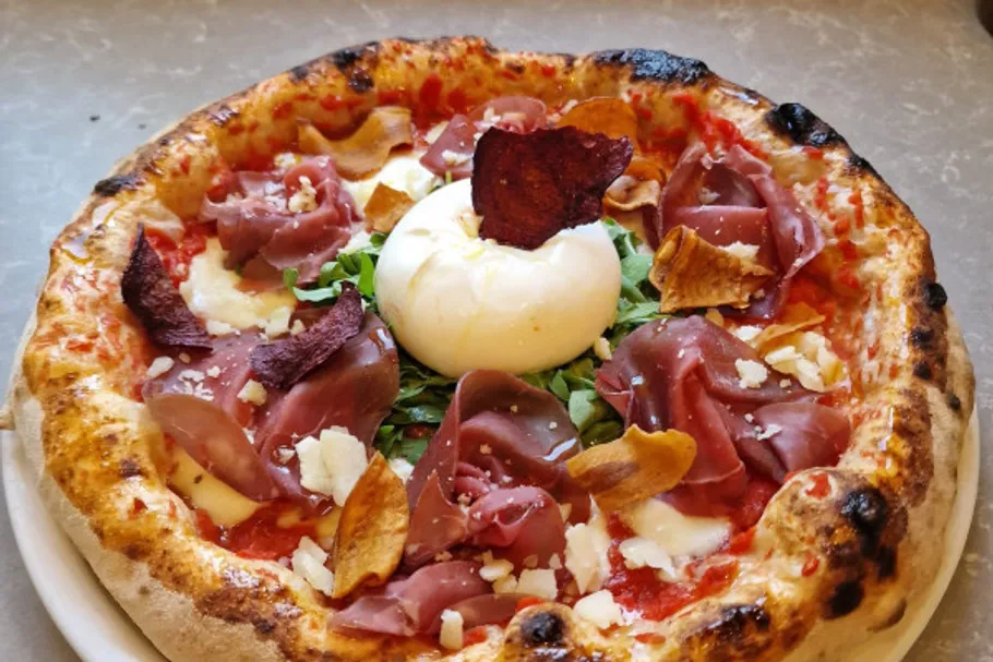 Pizza mit Burrata, Prosciutto und Rucola Belag.