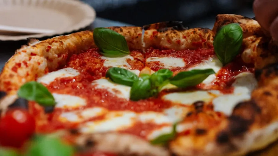 Pizza mit Basilikum auf einem Teller.