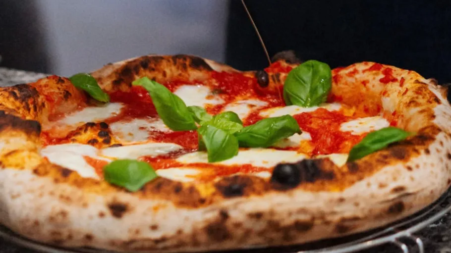 Pizza with basil leaves, served hot.