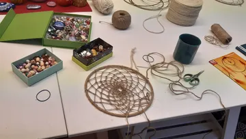 Bastelmaterialien und Traumfänger auf Tisch.