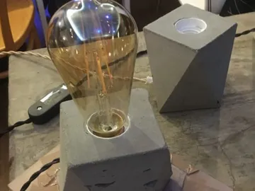 Glühlampe leuchtet auf einem Betonsockel auf einem Tisch.