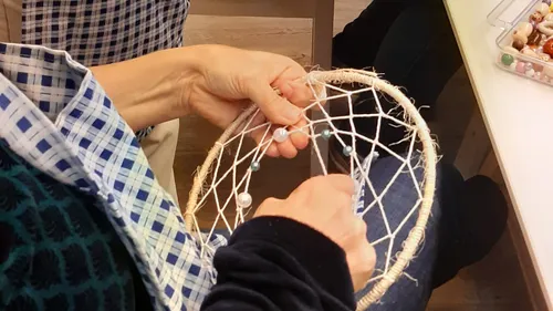 Person making a dreamcatcher with beads.