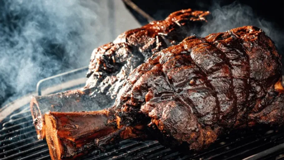 Smoked meat cooking on outdoor grill.