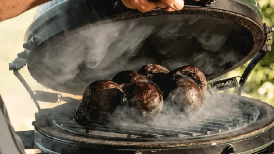 Grilled steaks smoking on outdoor barbecue.