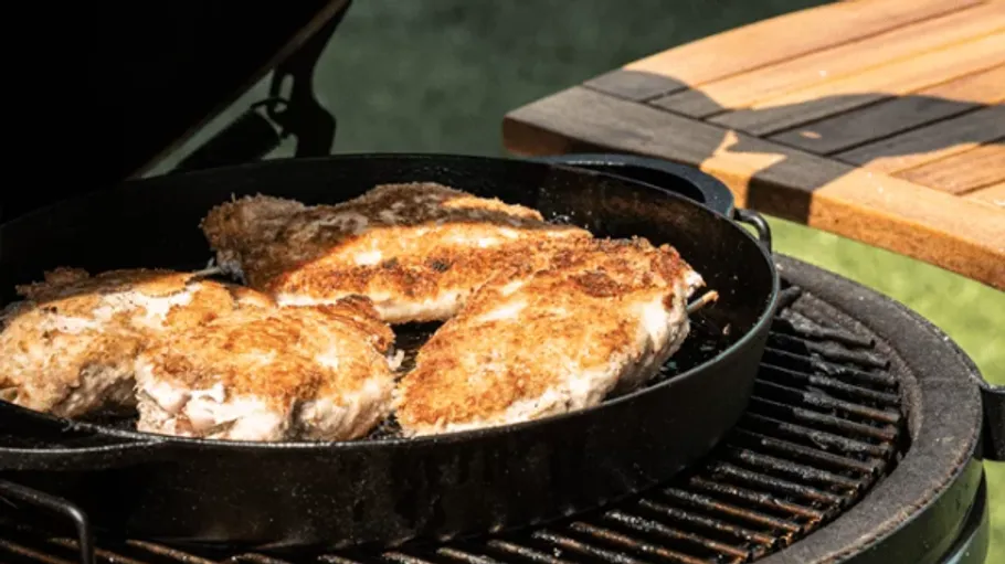 Grilled chicken in pan on barbecue grill.