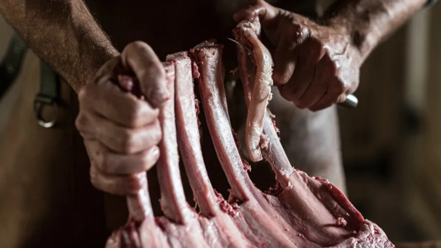 Person bearbeitet rohe Rippen, Fleisch zubereiten.