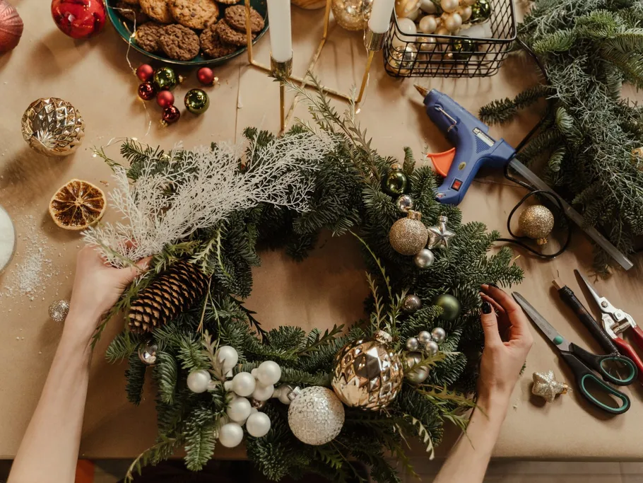 Kranz wird mit Ornamenten und Werkzeugen auf Tisch dekoriert.