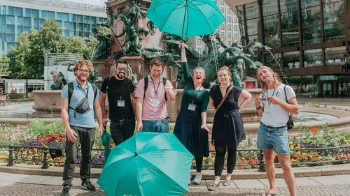 Gruppe mit Regenschirmen auf Stadtplatz.