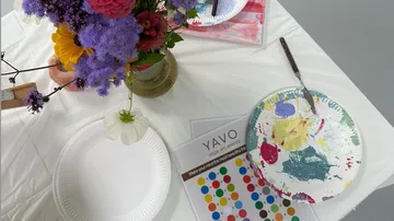 Blumen, Farbpalette und Papier auf Tisch.