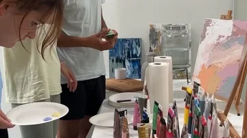 People painting at art class with supplies.