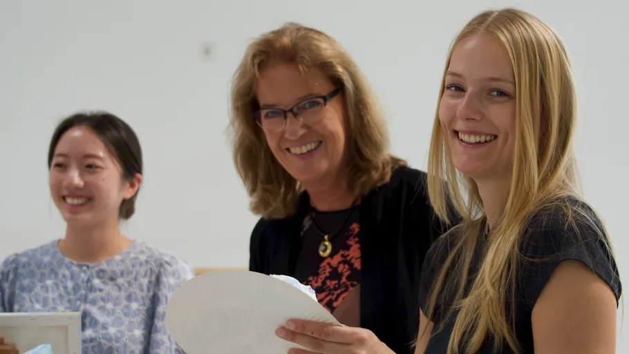 Three women smiling in an indoor setting.