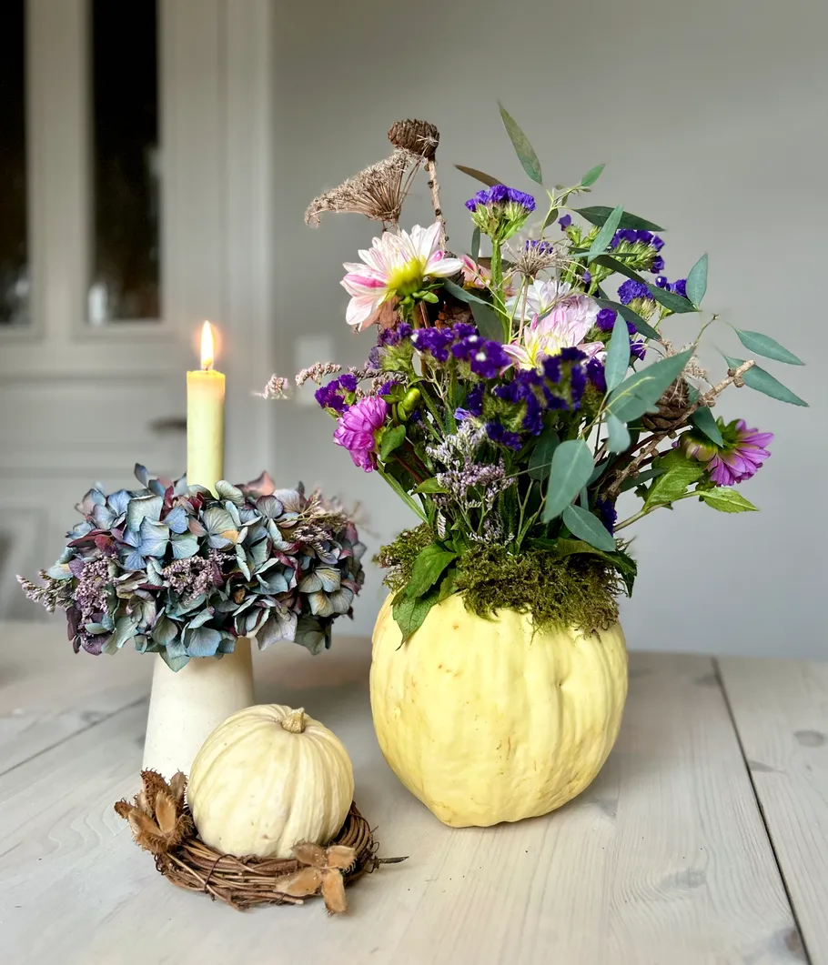 Flower arrangement with candle on wooden table.