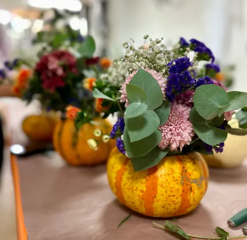 Kürbisvasen mit bunten Blumenarrangements.