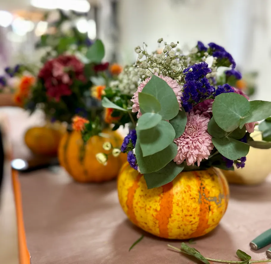 Pumpkin vases with colorful flower arrangements.