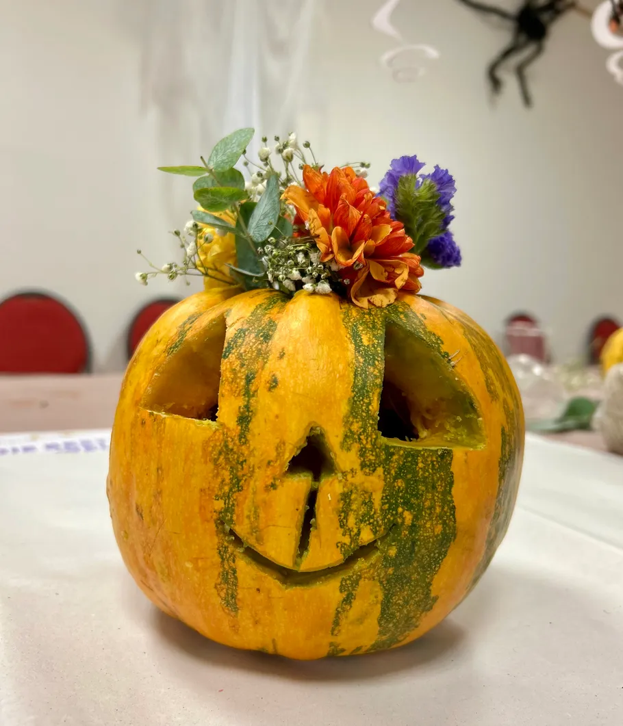 Carved pumpkin with flowers, indoor setting.