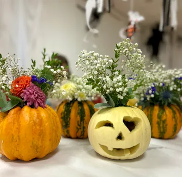 Kürbisse mit Blumen als Dekoration drinnen.