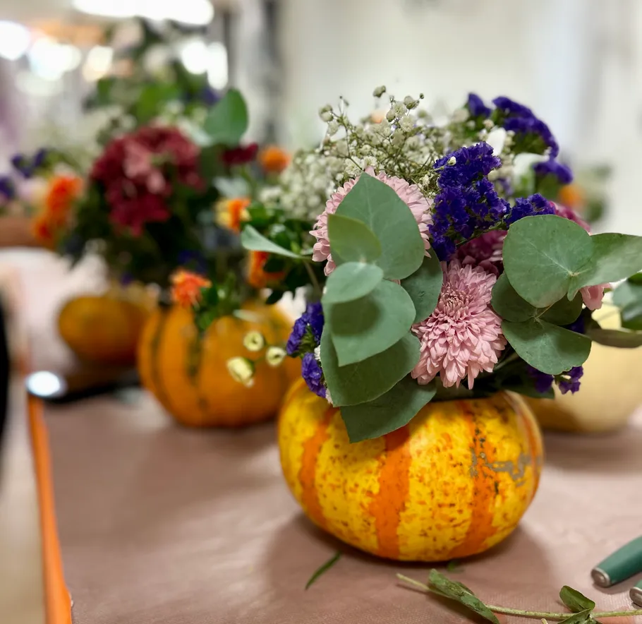 Pumpkins filled with flowers on table.
