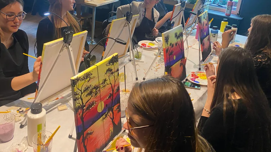 Women painting tropical sunset scenes together.
