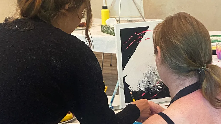 Zwei Frauen malen zusammen abstrakte Kunst.