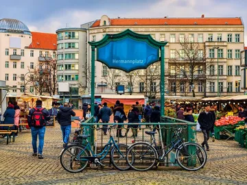 Marktplatz mit Leuten, Fahrrädern und Ständen für frisches Gemüse.