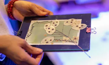 Person holding handmade card with dried flowers.