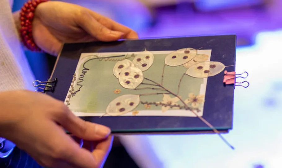 Person holding handmade card with dried flowers.