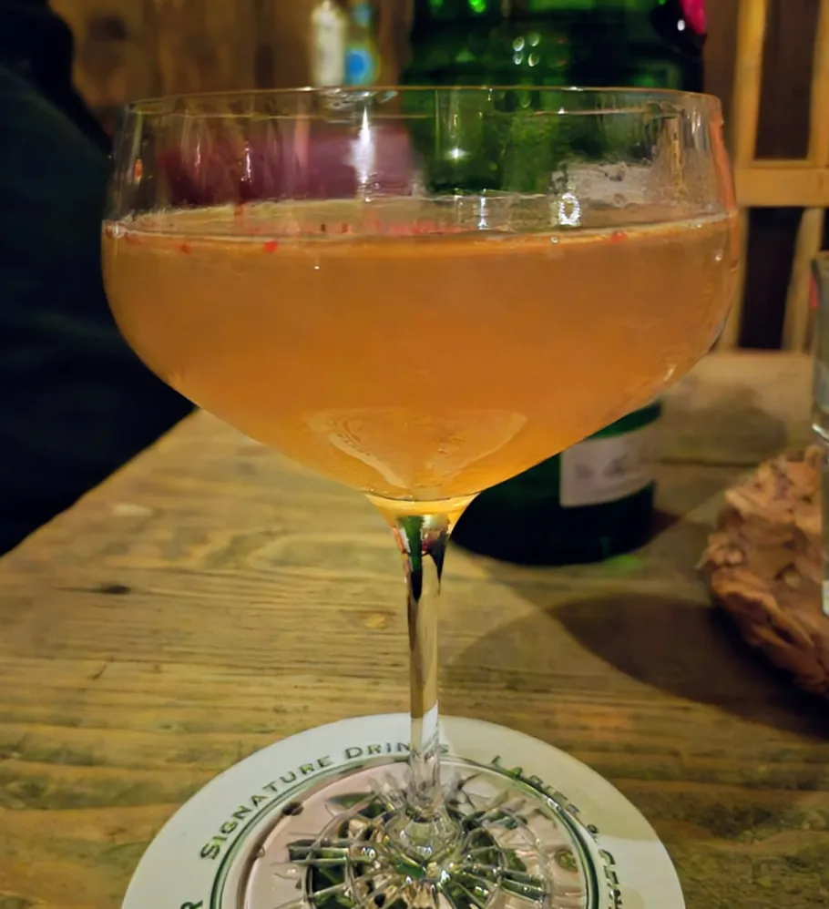 Cocktail glass with liquid on wooden table.