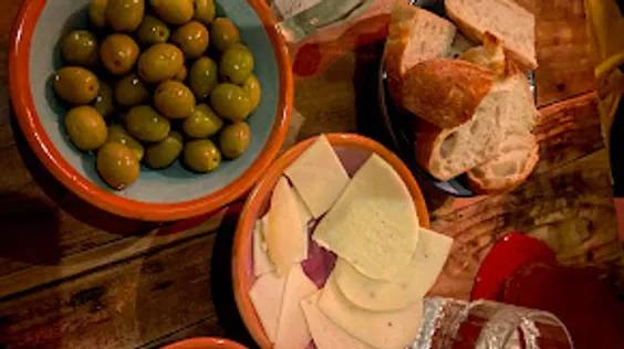 Olives, cheese, bread on wooden table.