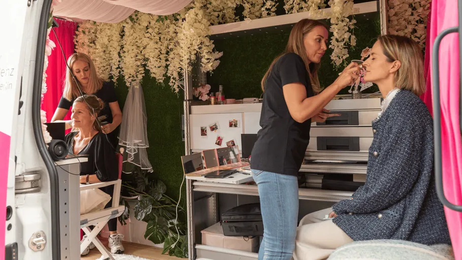 Women doing makeup inside decorated van.