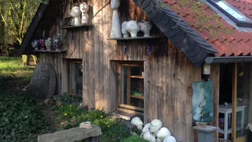 Holzhütte mit Skulpturen draußen im Garten.