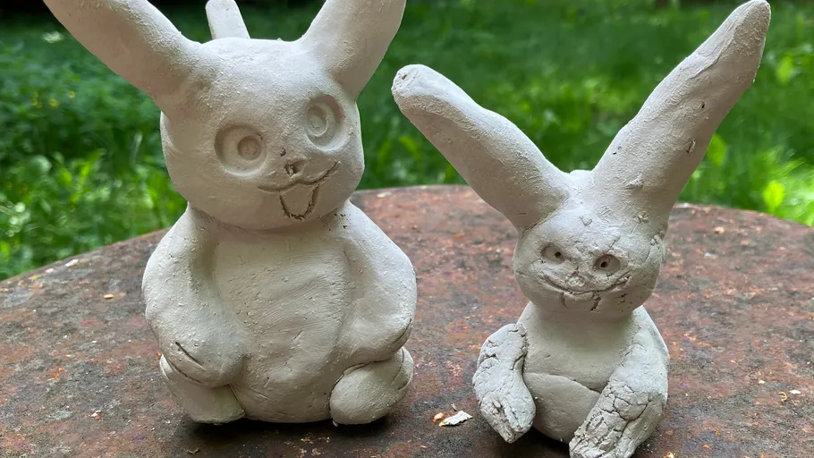 Zwei Ton-Hasenfiguren auf einem Tisch.