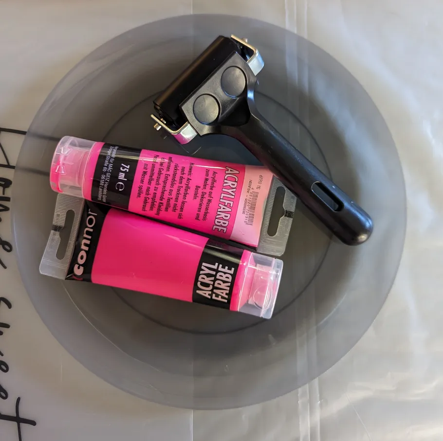 Two pink acrylic paint tubes on plate.